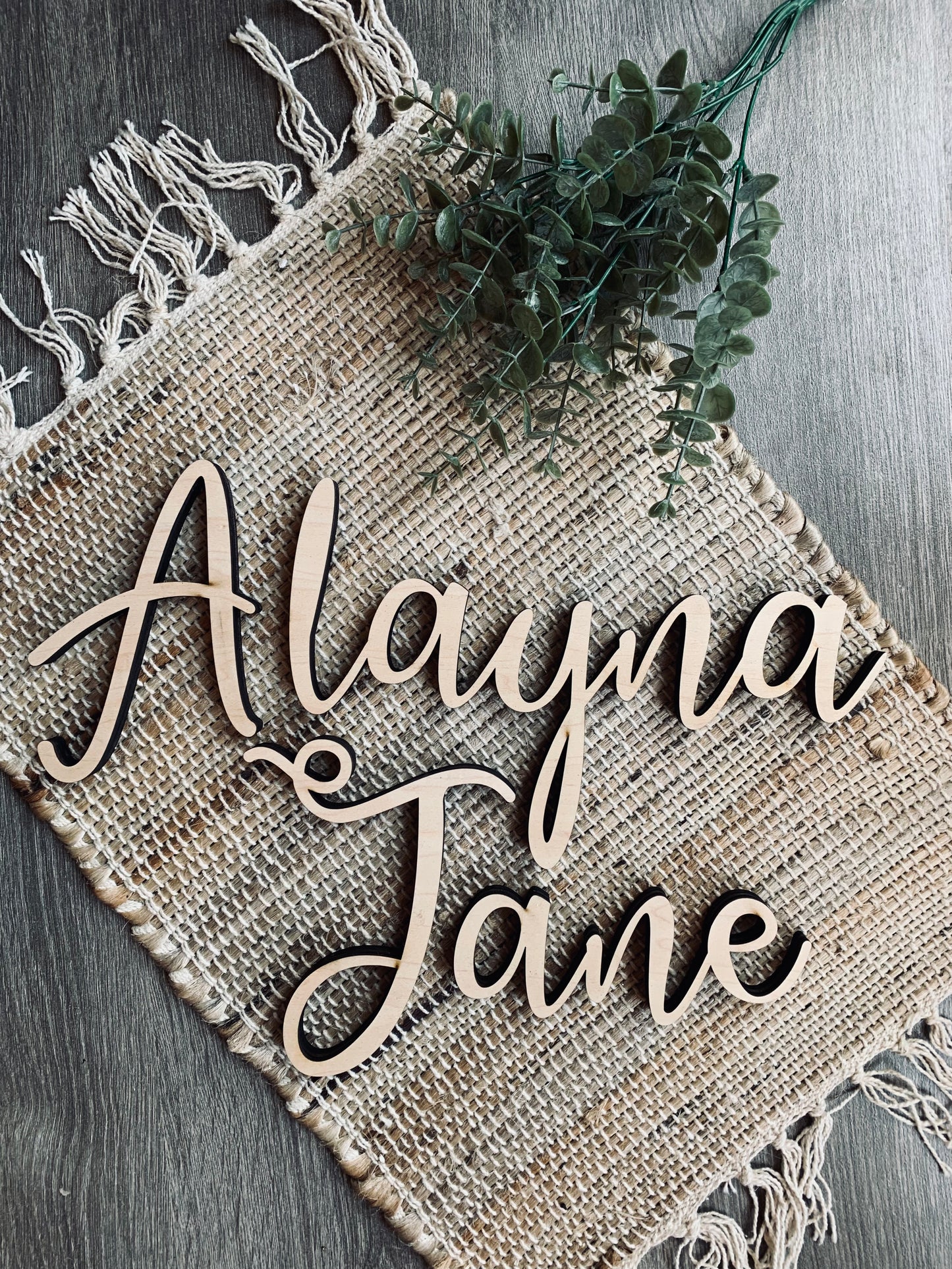 Custom wooden 3D cut letters spelling out the name 'Alayna Jane' placed on a burlap fabric.